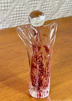 Full view of clear glass angel figurine with red swirl interior