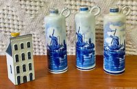 Group shot of three cylindrical Delft bottles and one KLM house bottle on wooden surface