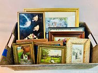 Group of framed artworks in bin