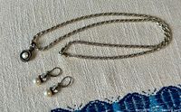 Necklace and both earrings laid out on fabric