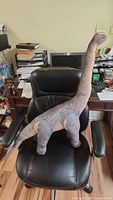 Full view of Brachiosaurus plush on chair showing size and overall condition