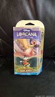 Front view of sealed Disney Lorcana Into the Inklands Ruby/Sapphire starter deck box