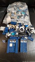 Bag and pile of assorted LEGO TARDIS parts on black surface