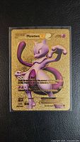 Front view of gold metal Mewtwo EX replica card in sleeve