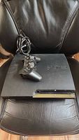 PS3 Slim console and DualShock 3 controller on chair