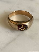 Ring angled view showing emblem and gold tone