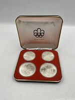 Open presentation case displaying four coins