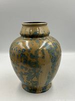 Front view of beige ceramic vase with blue crystalline glaze