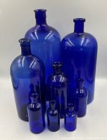Eight cobalt blue glass bottles grouped, showing varying heights