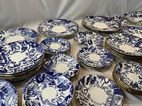 Group of stacked plates and bowls showing pattern and gilt rim