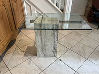 Angled view of travertine pedestal base and glass top