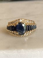 Front view of ring showing central oval sapphire, baguette sapphires, and diamond borders