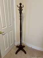 Full view of tall wooden hall coat tree against wall