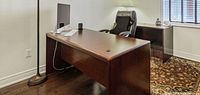 Front view of rectangular executive desk showing top surface, modesty panel and chair for scale
