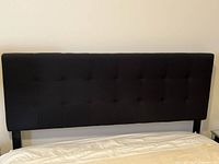 Front view of black upholstered headboard attached to bed frame