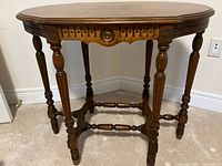 Full view of oval hardwood table showing legs, apron, finish