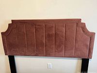 Front view of pink velour queen headboard mounted on black legs