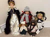 Group shot of all five porcelain dolls showing relative sizes and outfits