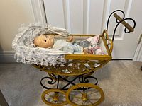 Doll in yellow metal carriage showing overall appearance