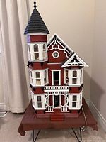 Full exterior of red and white Victorian dollhouse
