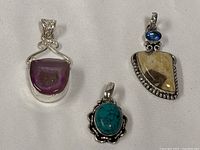 Group view of three gemstone pendants showing relative sizes and designs