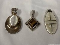 Front view of three silver tone pendants
