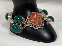 Front view of bracelet showing green chalcedony cabochons and orange druzy center stone in sterling silver setting