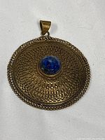 front of brass pendant showing filigree and stone