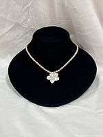 Full view of necklace on display bust showing pearl strand and abalone pendant