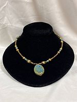 Full necklace on display bust showing bead arrangement and pendant