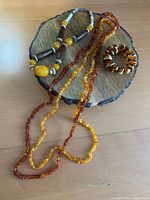 All four amber jewellery pieces displayed on wood stand