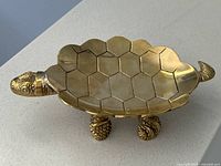 Side view of brass turtle dish showing shell pattern and feet