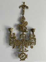 Full view of cast brass wall sconce with two candle cups and St. George figure