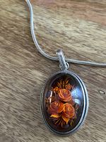close view of amber pendant showing carved roses and silver bezel