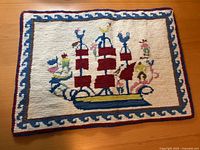 Full view of embroidered textile front showing sailboat motif and borders