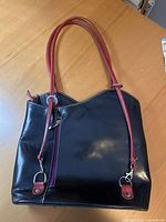 Front view of black leather purse with red straps