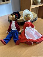 Both dolls lying side by side showing full outfits