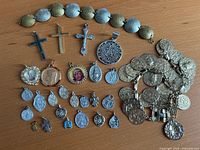 Overall view of both coin bracelets, crosses, Mayan calendar pendant and medal charms