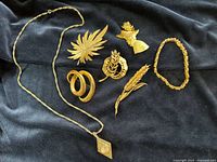 Entire lot laid out on dark fabric showing all brooches, bracelet and pendant watch on chain