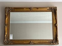 Full view of gold framed rectangular beveled mirror on wall
