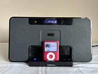 Front view of Altec Lansing inMotion dock with pink iPod Nano seated, LCD and iPod screens on