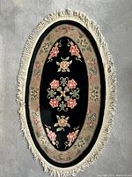 Full view of oval wool rug showing floral design and fringe
