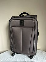 Front view of grey Travelpro suitcase showing wheels and handle