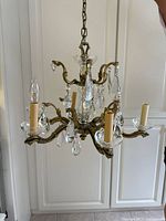 Full view of brass chandelier with crystal prisms and four candle sleeves
