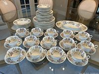 Full set on glass table showing plates, bowls, cups, saucers, platters
