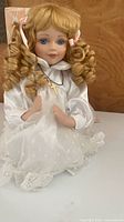 Front view of kneeling porcelain doll showing hair, dress, necklace