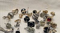 Assorted cufflinks, tie bars and earrings displayed on textured surface