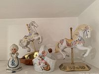Two carousel horses, bell and rabbit basket on shelf