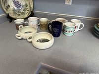 Group of mugs and soup bowls on countertop
