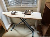 Full view of ironing board with iron and steamer on top